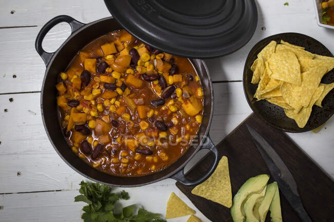 Sweet potatoes chili in pan with avocado and nachos — Stock Photo
