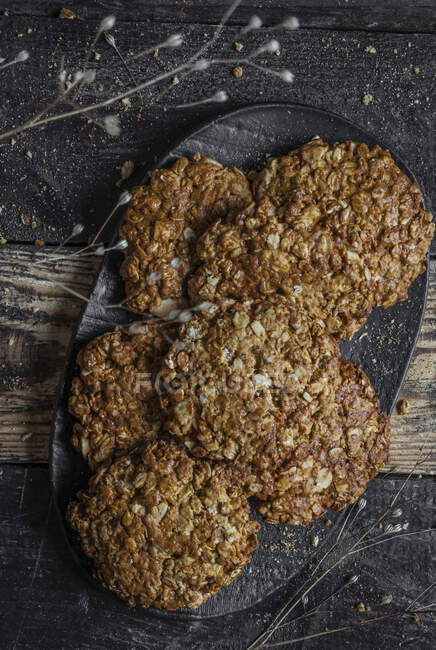 Oatmeal cookies on black plate and wooden background — Stock Photo