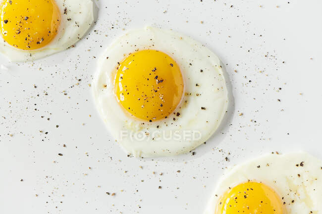 Three sunnyside eggs with pepper sprinkled over top — Stock Photo