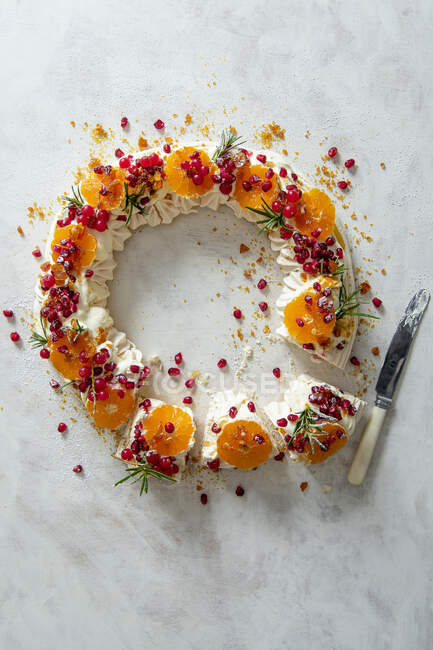 Meringues wreath with whipped cream, pomegranate, satsumas, redcurrants and praline — Stock Photo