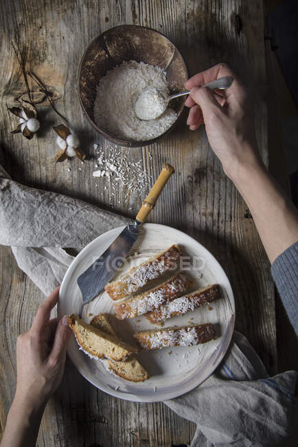 Polvilhando pedaços de bolo de coco com coco ralado — Fotografia de Stock
