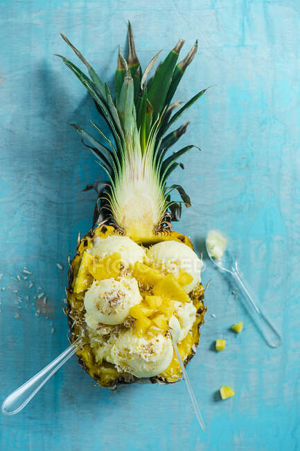 Ананас і кокосовий сорбет в ананасі з ананасовими шматочками і підсмаженим кокосом — стокове фото