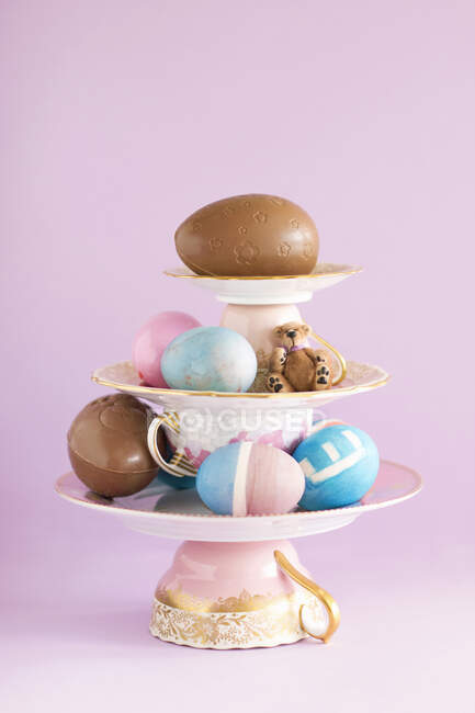 Composição da peça central de porcelana, ovos de Páscoa coloridos e ovos de chocolate — Fotografia de Stock