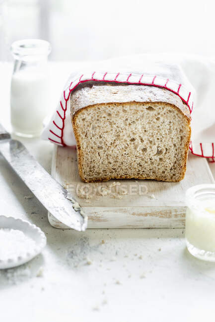 Wholemeal bread loaf half covered with cloth — Stock Photo