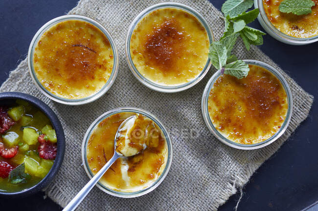 Several creme brulee desserts and fruit compote in bowls — Stock Photo