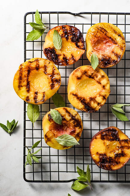 Grilled Peaches with mint leaves on cooling rack — Stock Photo