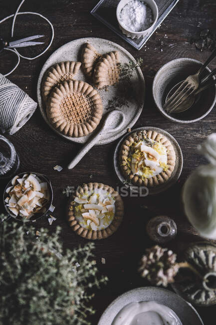 Cake tartlets with vanilla pudding and coconut chips on a rustic background — Stock Photo