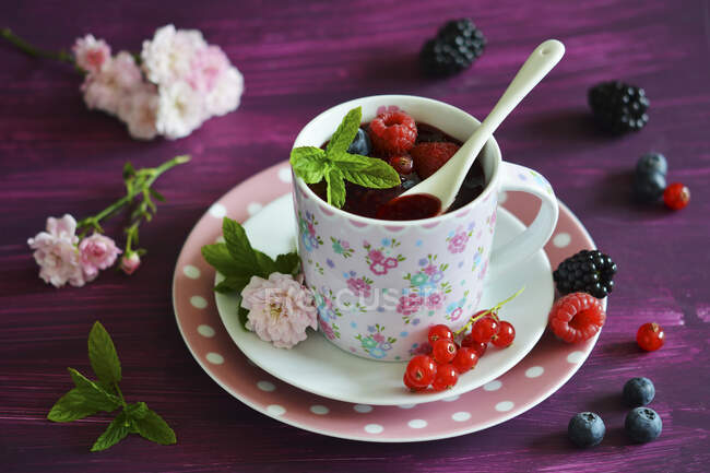 Grumos vermelhos em uma xícara com frutas frescas — Fotografia de Stock