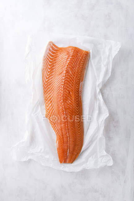 Raw fillet of salmon on baking paper — Stock Photo