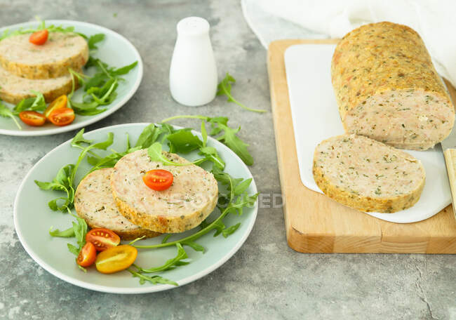 Baked turkey meatloaf with aromatic herbs served with rocket and tomatoes — Stock Photo