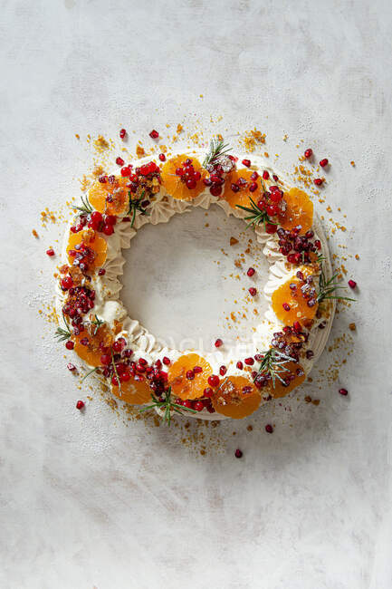 Meringue wreath with whipped cream, pomegranate, satsumas, redcurrants and praline — Stock Photo