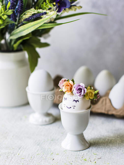 Huevos de Pascua con decoraciones florales en copas de huevo - foto de stock