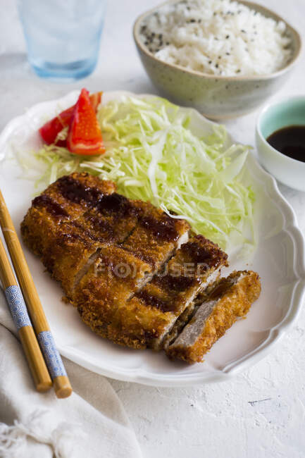 Нарезанный тонкацу с нарезанной капустой и палочками для еды — стоковое фото