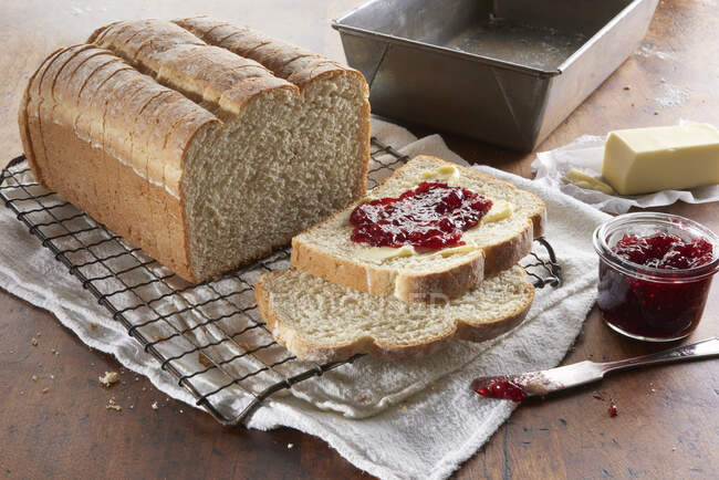 Frisch gebackenes Brot, in Scheiben geschnitten und mit Butter und Beerenmarmelade belegt — Stockfoto