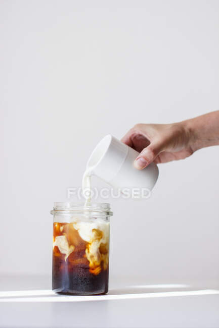 Холодный кофе: молоко добавляется в стакан холодного кофе — стоковое фото