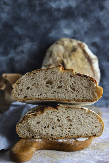Una pagnotta dimezzata di pane di pasta madre su una tavola di legno — Foto stock