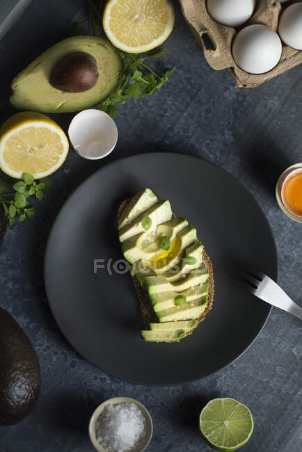 A slice of bread topped with avocado, lime, olive oil and fleur de sel — Stock Photo