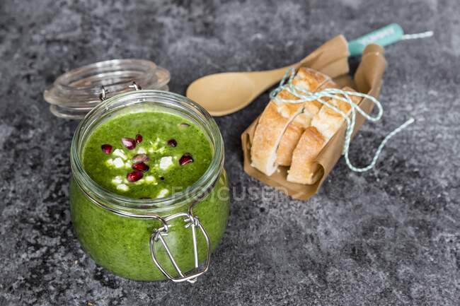 Green cabbage soup in a glass jar with pomegranate seeds and feta cubes — Stock Photo
