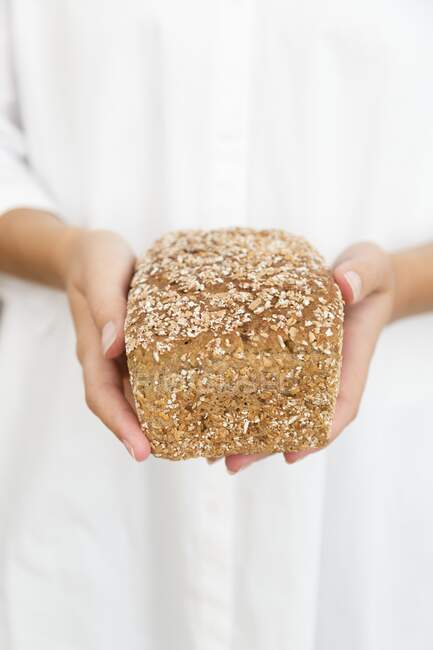 A woman holding a loaf of oat bread — Stock Photo