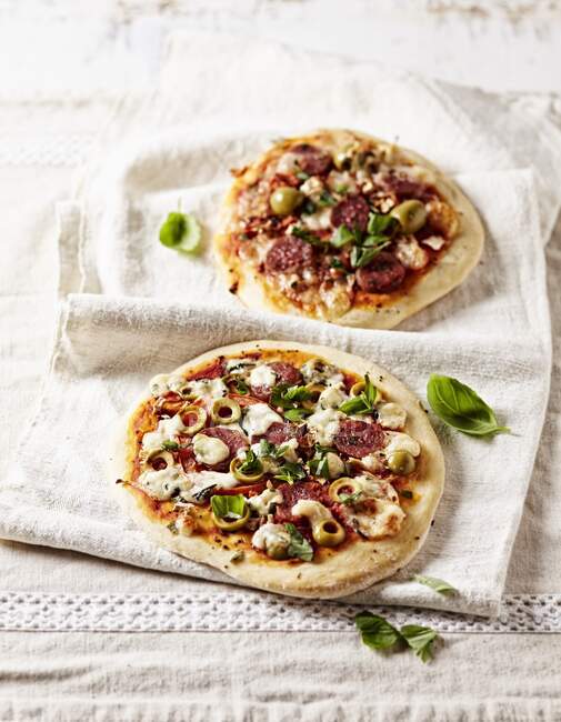 Due pizze rustiche con chorizo, olive verdi e foglie di basilico — Foto stock