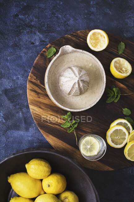 Juicer de limão, hortelã e limões frescos na tábua de cortar — Fotografia de Stock