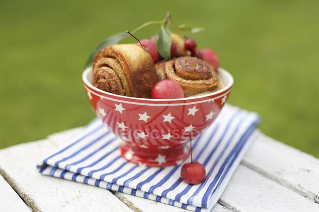 Cinnamons rolls in a red bowl and paradise apples — Stock Photo