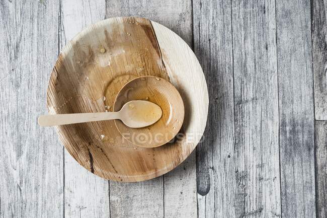 Remains of honey on a wooden plate with a spoon — Stock Photo