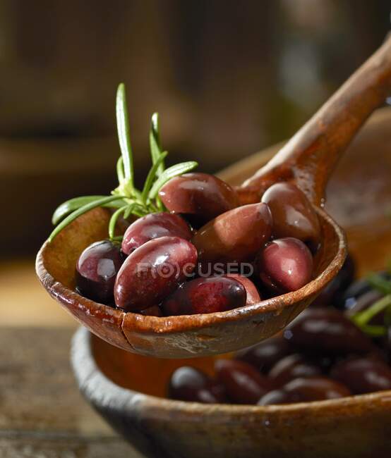 Kalamata olives with rosemary in a wooden ladle — Stock Photo