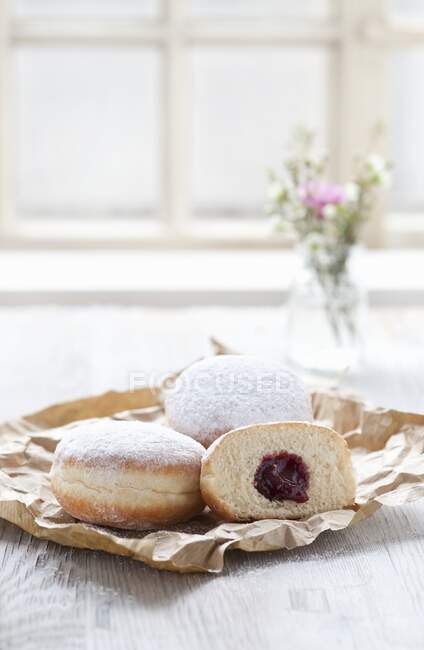 Jam doughnuts on a paper bag next to a window — Stock Photo