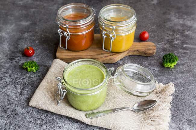 Various colourful soups in glass jars (broccoli soup, tomato soup, pumpkin soup)) — Stock Photo