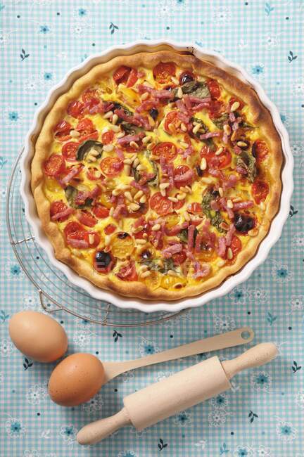 Quiche with cherry tomatoes, spinach, bacon and pine nuts — Stock Photo