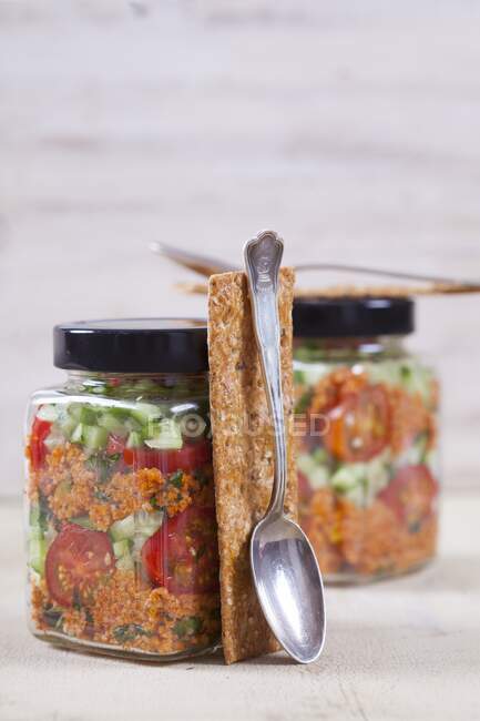 Bulgur wheat salad with pomegranate syrup, onions, cucumber, tomatoes, parsley and mint in glass jar — Stock Photo