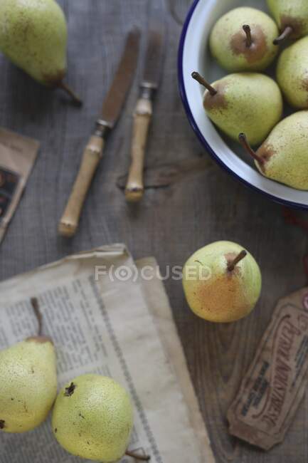 Pears in a metal bowl and on the newspaper — Stock Photo