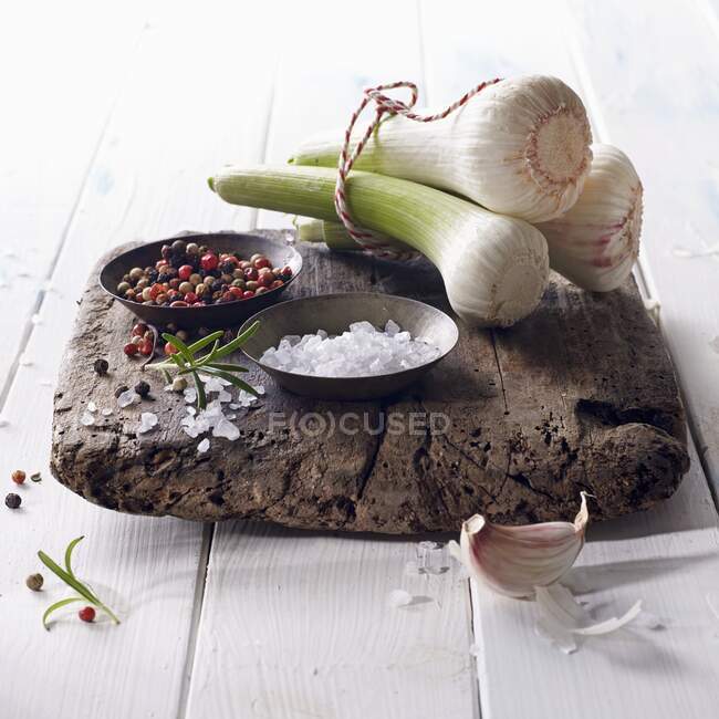 Bulbi freschi di aglio con sale e pepe colorato su una tavola di legno — Foto stock