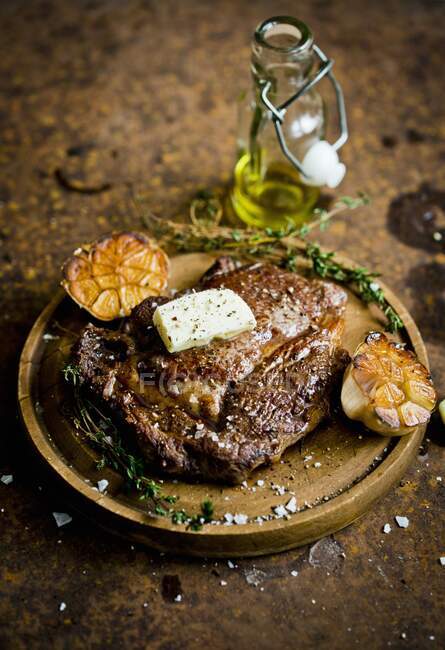 Un steak à l'ail et au beurre sur une planche de bois — Photo de stock