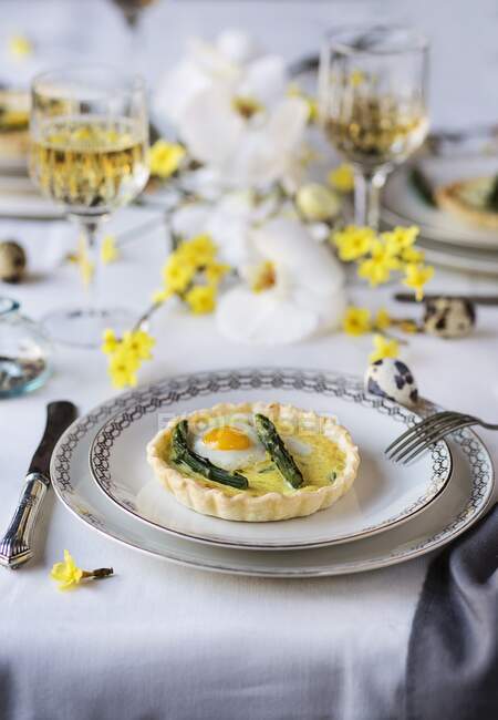 Asparagus quiche with fried quail egg on a dining table set for Easter — Stock Photo