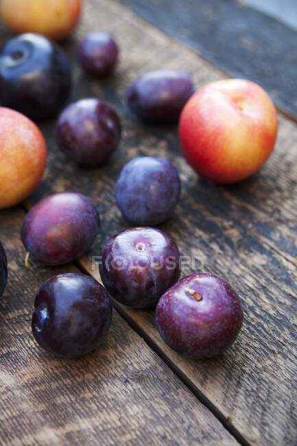 Assorted plums on rustic wooden surface — Stock Photo