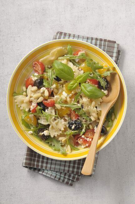 Салат из пасты с помидорами черри, ругулой, оливками, рикоттой и кедровыми орехами — стоковое фото