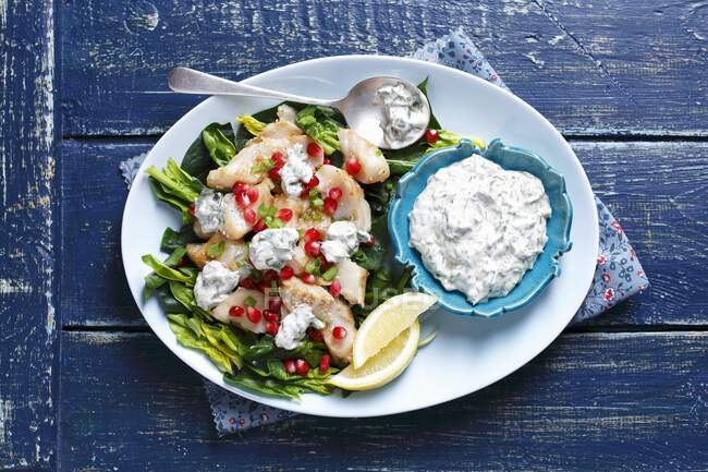 Fried cod with spinach, pomegranate and herb yogurt sauce — Stock Photo