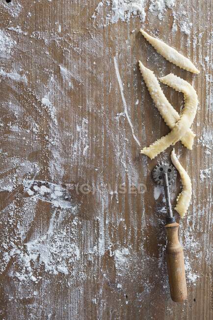 Strips of pastry on a floured wooden board — Stock Photo