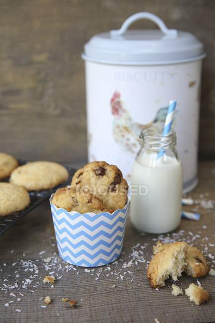 Biscotti al cocco con gocce di cioccolato e una bottiglia di latte — Foto stock