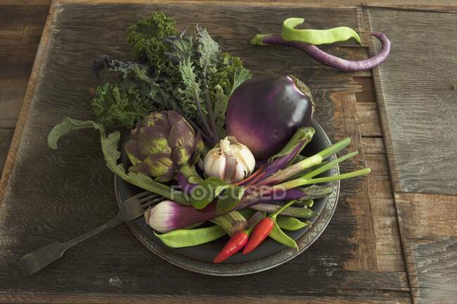 A bowl of vegetables with aubergines, artichoke, garlic and chillies — Stock Photo