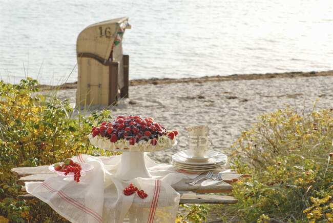 Летний ягодный торт на деревянной скамейке на пляже — стоковое фото