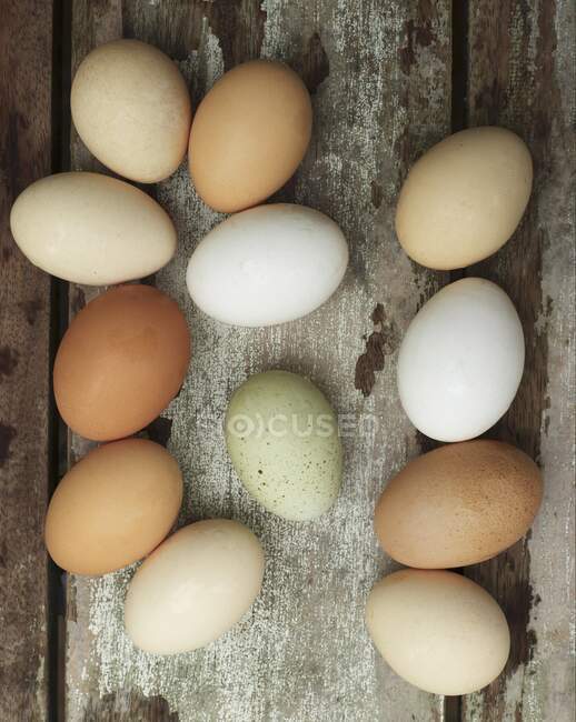 Different-coloured fresh eggs on a wooden background — Stock Photo