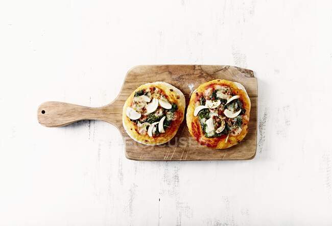 Duas mini pizzas com espinafre e alho em uma placa de cozinha — Fotografia de Stock