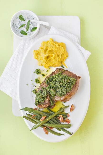 Pierna de cordero con una corteza de hierbas, salsa, zanahoria y puré de papa y judías verdes - foto de stock