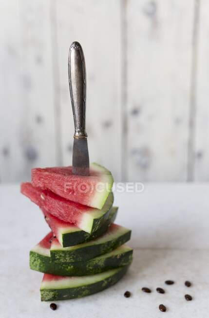 Morceaux en forme de triangle de pastèque avec un couteau collé à travers eux — Photo de stock