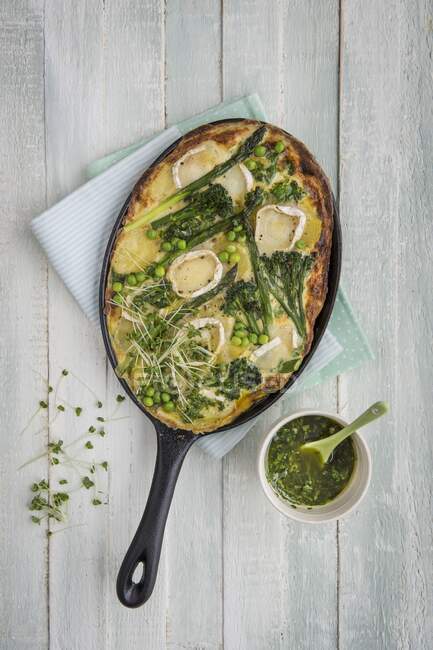 Potato and egg frittata with spring vegetables and gats cheese, basil oil on a side — Stock Photo