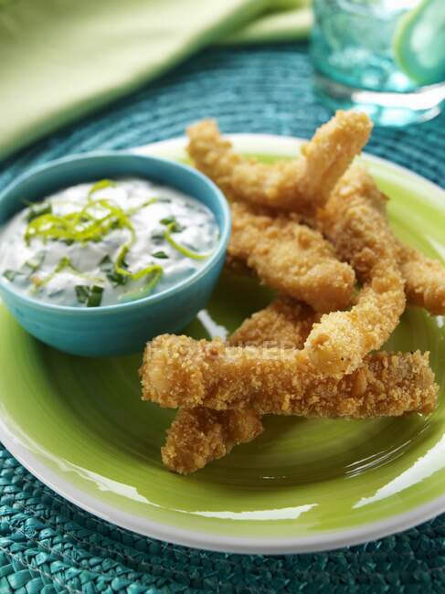 A plate of salmon goujons with dipping sauce — Stock Photo