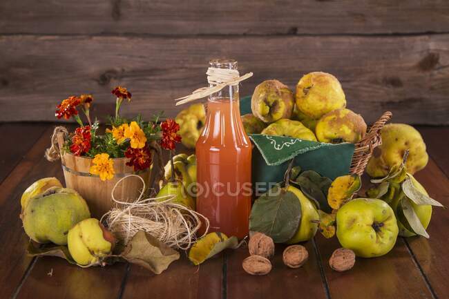 Still life with quinces, quince juice, walnuts and flowers — Stock Photo